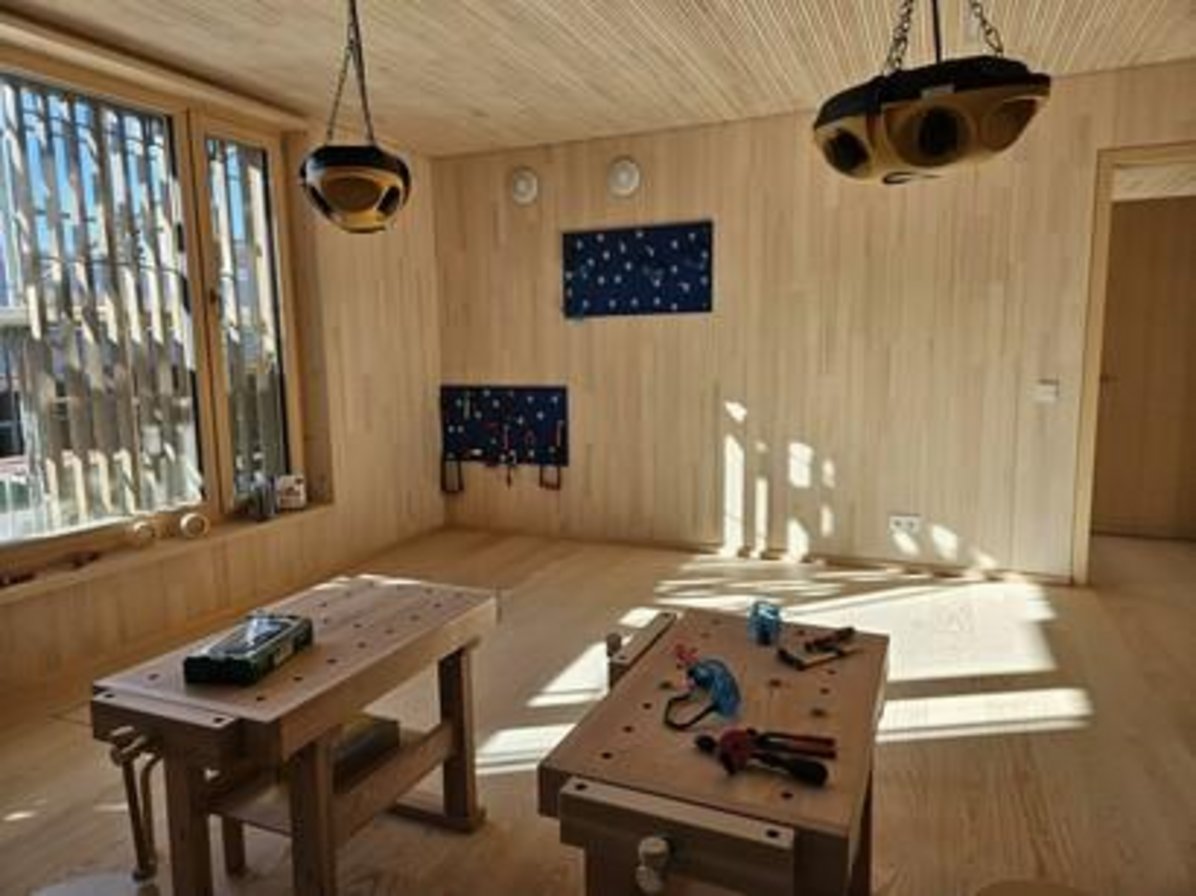 Raum komplett mit Holz verleidet, zwei Werkbänken und Werkzeug an der Wand