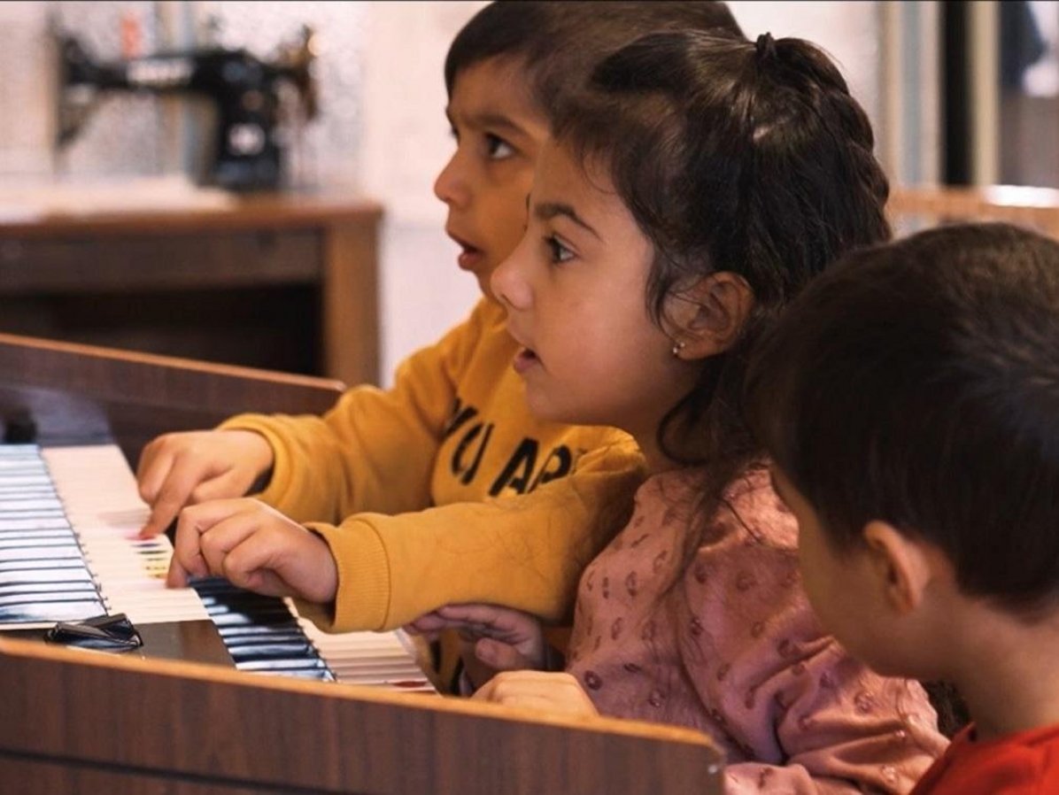 Drei Kinder spielen an einer Heimorgel.