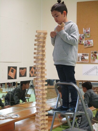 Kind stapelt Holzklötzchen zu einem hohen Turm