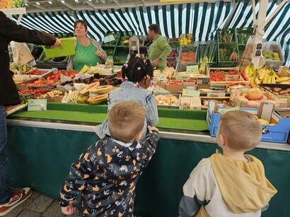 drei Kinder vor einem Marktstand