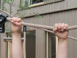 zwei Kinderhände mit halbem Unterarm an einem Seil hängend