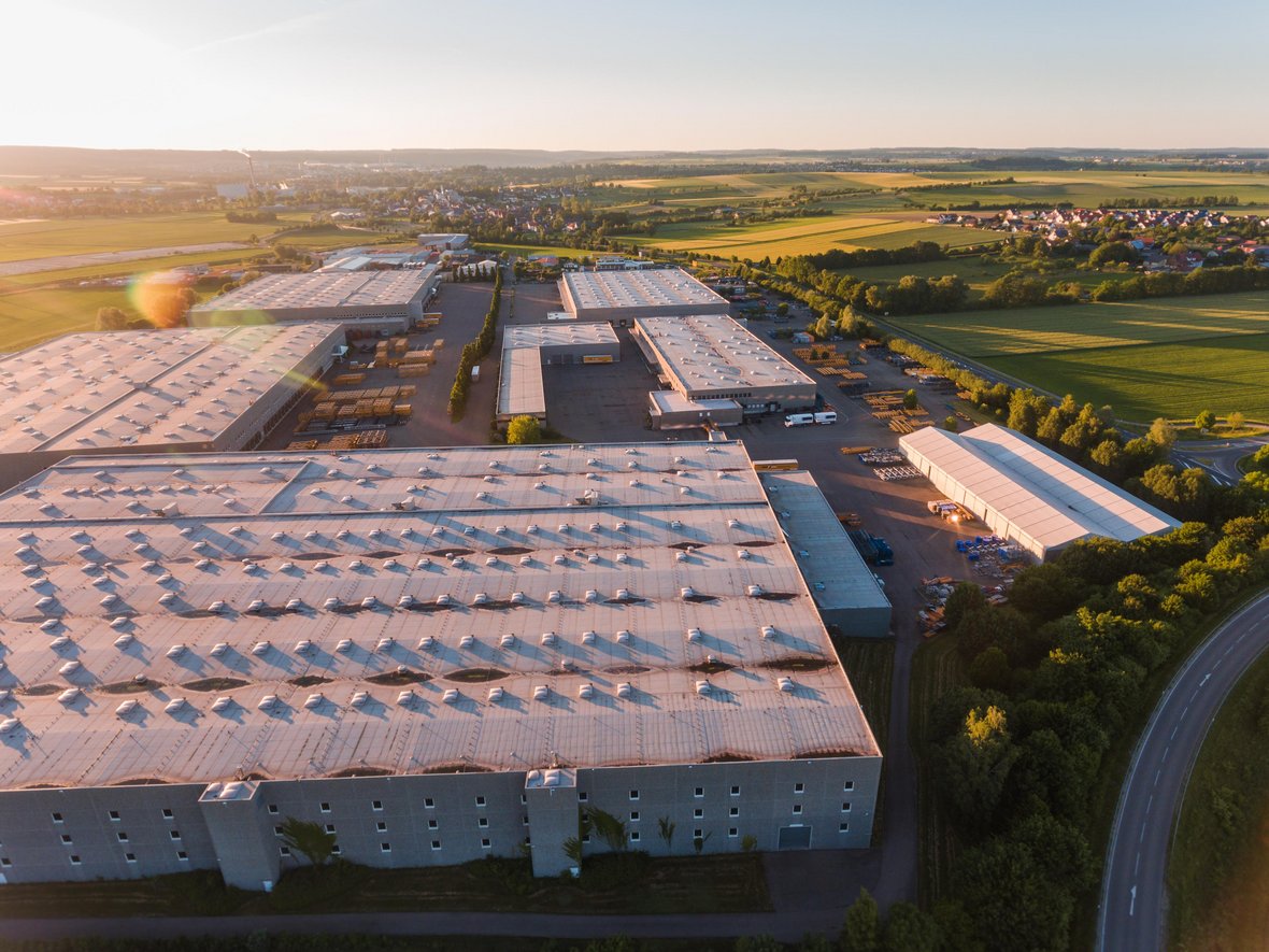 Ein Industriegebiet von oben, links der Sonnenuntergang, rechts eine Ortschaft und Felder
