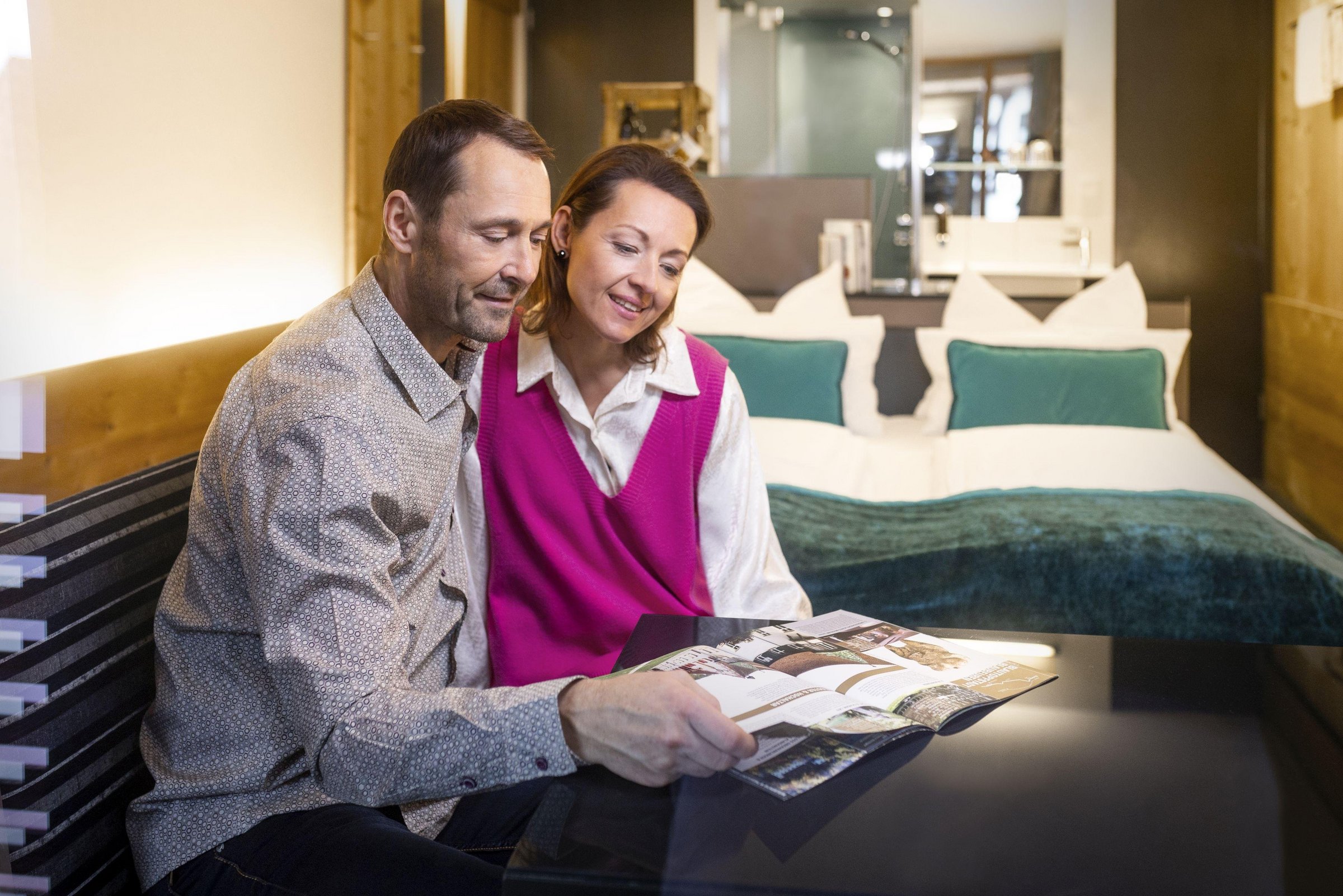 Zwei Personen sitzen in einem Hotelzimmer und schauen sich einen Prospekt an