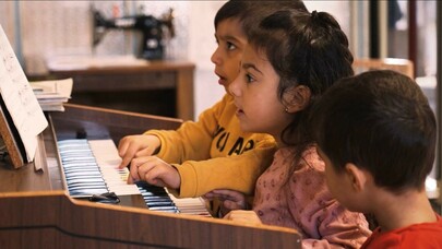 Drei Kinder spielen an einer Heimorgel.