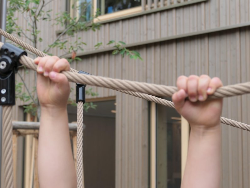 zwei Kinderhände halten sich an einem Seil fest