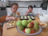 Zwei Kinder schneiden Äpfel und backen Muffins.