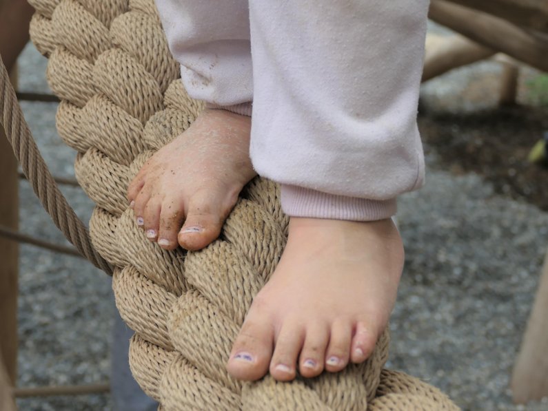 Kinderfüße barfuß auf einem dicken Tau balancierend