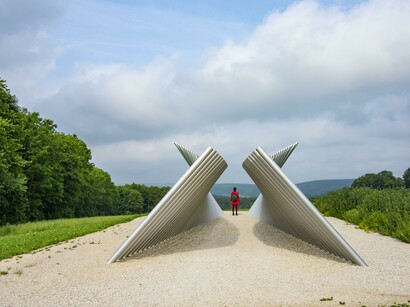 Kunstwerk in Landschaft, Person steht zwischen Metallrohren