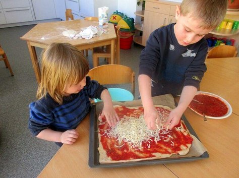 Zwei Kinder belegen eine Pizza