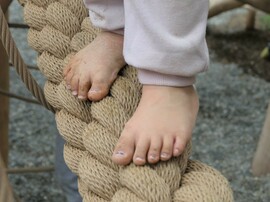 Kinderfüße barfuß auf einem dicken Tau balancierend