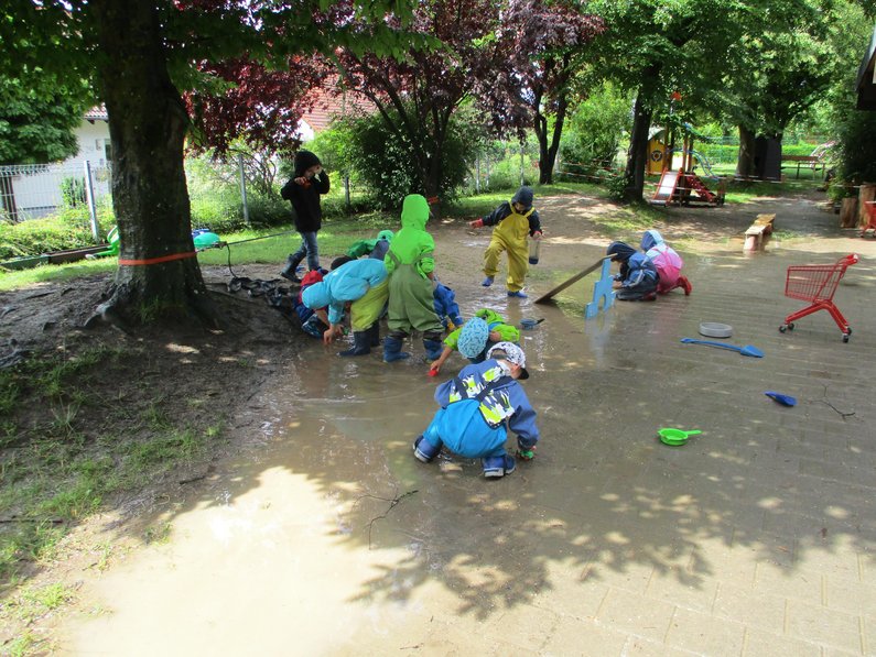 Spielende Kinder mit Matschhosen in Wasserpfütze